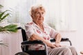 Ailing woman dressed in a blouse with flower pattern is sitting in a wheelchair in her home Royalty Free Stock Photo