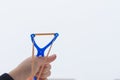 Aims a slingshot with a stretched elastic band at the target