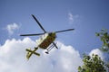 The air ambulance, service arrives at the scene of an accident. Flying yellow medical ambulance helicopter over the trees.