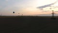 Air balloons flying over fields at dusk electric cables bellow industrialization