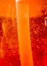 Air bubbles within orange dishwashing liquid with plastic tube inside. Abstract ember background. Royalty Free Stock Photo