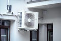 Air condition outdoor unit compressor installed outside the house hanging on a wall between windows Royalty Free Stock Photo