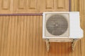 Air conditioner condensing unit hanging on the wooden wall. Air conditioner compressor installation Royalty Free Stock Photo