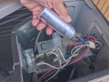 Air conditioner repair by technician. The technician replace the capacity run of air conditioner. Hand holding the capacitor run