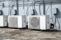 Air conditioner units HVAC on a roof of industrial building with blue sky and clouds in the background.