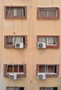 Air conditioning external units with large fans on old building facade wall near windows, many untidy cables near