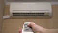 Air conditioning in the house to adjust the temperature in the room. A woman turns on the air conditioner using a remote Royalty Free Stock Photo