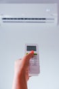 Air conditioning. A woman holds a remote control from an air conditioner in her hands. Wall mounted air conditioner unit in the