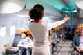 Air hostess or airline staff woman demostrate and guide the emergency exit of airplane to the passenger before take of the flight Royalty Free Stock Photo