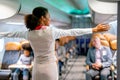 Air hostess or airline staff woman demostrate and guide the emergency exit of airplane to the passenger before take of the flight Royalty Free Stock Photo