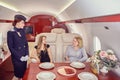 Air hostess serves business class passengers inside airplane. Royalty Free Stock Photo