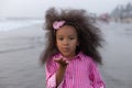 Air kiss. Playful girl with beautiful pink hair hoop in pink suit against background of sea.