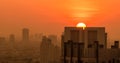 Air pollution. Smog and fine dust of pm2.5 covered city in the morning with orange sunrise sky. Cityscape with polluted air. Dirty