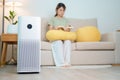 Air Purifier with woman read and relax on sofa. Purification system for filter and cleaning dust PM2.5 HEPA and virus in home.