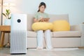 Air Purifier with woman relax and use tablet on sofa. Purification system for filter and cleaning dust PM2.5 HEPA and virus in