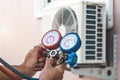 Air repair mechanic using measuring pressure gauge equipment for filling home air conditioner Royalty Free Stock Photo