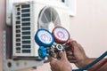 Air repair mechanic using measuring pressure gauge equipment for filling home air conditioner Royalty Free Stock Photo