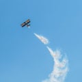 A small biplane airplane doing acrobatic stunts against the blue sky