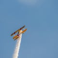 A small biplane airplane doing acrobatic stunts against the blue sky