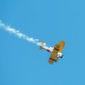 A small biplane airplane doing acrobatic stunts against the blue sky