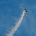 A small biplane airplane doing acrobatic stunts against the blue sky