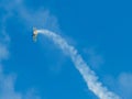 A small biplane airplane doing acrobatic stunts against the blue sky