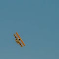 A small biplane airplane doing acrobatic stunts against the blue sky