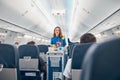 Air stewardess serving food on the board commercial airplane Royalty Free Stock Photo