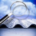 Air testing and monitoring activity around a dangerous asbestos roof - concept image with magnifying glass