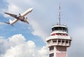 Air traffic control tower in international airport with passenger airplane jet taking off