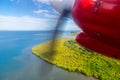 Air travel in Fiji, Melanesia, Oceania. View of a green remote tropical island from a window of a small propeller airplane.