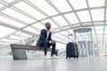 Air Travels Concept. Smiling African American Male Sitting On Bench At Airport Royalty Free Stock Photo
