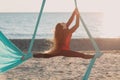 Air yoga on the open air beach. Woman doing split on hammock.