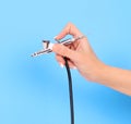 Airbrush in hand over blue background Royalty Free Stock Photo