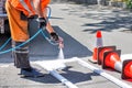 A road worker paints a white road marking of a pedestrian crossing with an airbrush on a sunny day Royalty Free Stock Photo