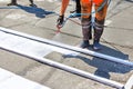 A road worker paints a white road marking of a pedestrian crossing using a wooden frame template and an airbrush Royalty Free Stock Photo