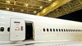 Aircraft cabin door opens between rows of windows during maintenance in hangar at night Royalty Free Stock Photo