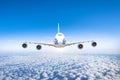 Aircraft flying at flight level high in the sky above the clouds and blue sky. View directly in front, exactly