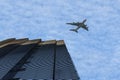 Aircraft flying over modern skyscraper building in the business district at a bright sunny day on the blue cloudy sky background. Royalty Free Stock Photo