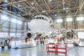 Aircraft inside the aviation hangar, maintenance service. Airplane technician worker working around. Bright light outside the gate