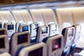 Aircraft interior with seats and blank touch screens displays. Royalty Free Stock Photo