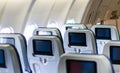Aircraft interior with seats and blank touch screens displays. Royalty Free Stock Photo