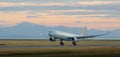 Aircraft landing at YVR at dusk with mountains in the background. Royalty Free Stock Photo