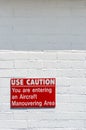 Aircraft manouvering red and white warning sign hung on painted brick wall. Royalty Free Stock Photo