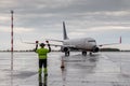 Aircraft marshalling at the aiport apron in rainy weather