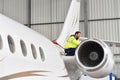 Aircraft mechanic inspects and checks the technology of a jet in a hangar at the airport