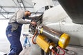 Aircraft mechanic repairs an aircraft engine in an airport hangar Royalty Free Stock Photo