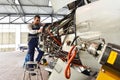 Aircraft mechanic repairs an aircraft engine in an airport hangar Royalty Free Stock Photo