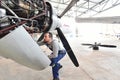 Aircraft mechanic repairs an aircraft engine in an airport hangar