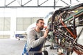 Aircraft mechanic repairs an aircraft engine in an airport hangar